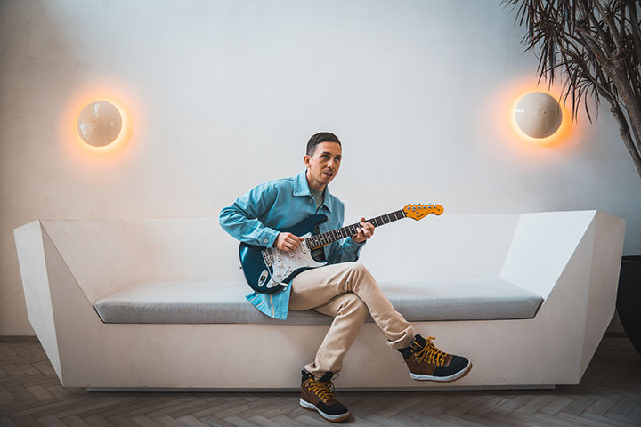 Cory Wong playing guitar on a sofa